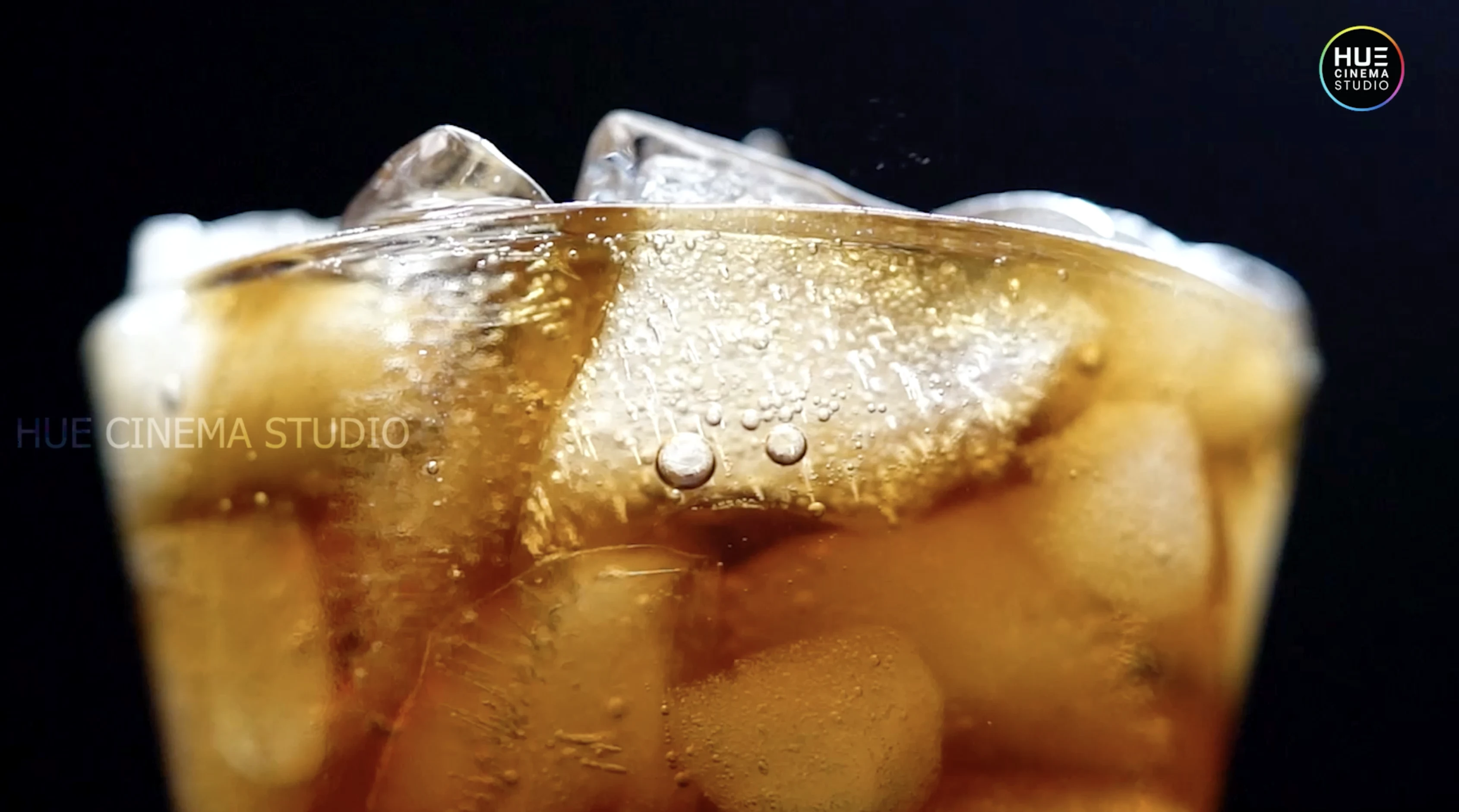 Close-up of a Coca-Cola pour over ice with rising soda bubbles, from the Alkor Cyber Space soft drinks b-roll showreel by Hue Cinema Studio.