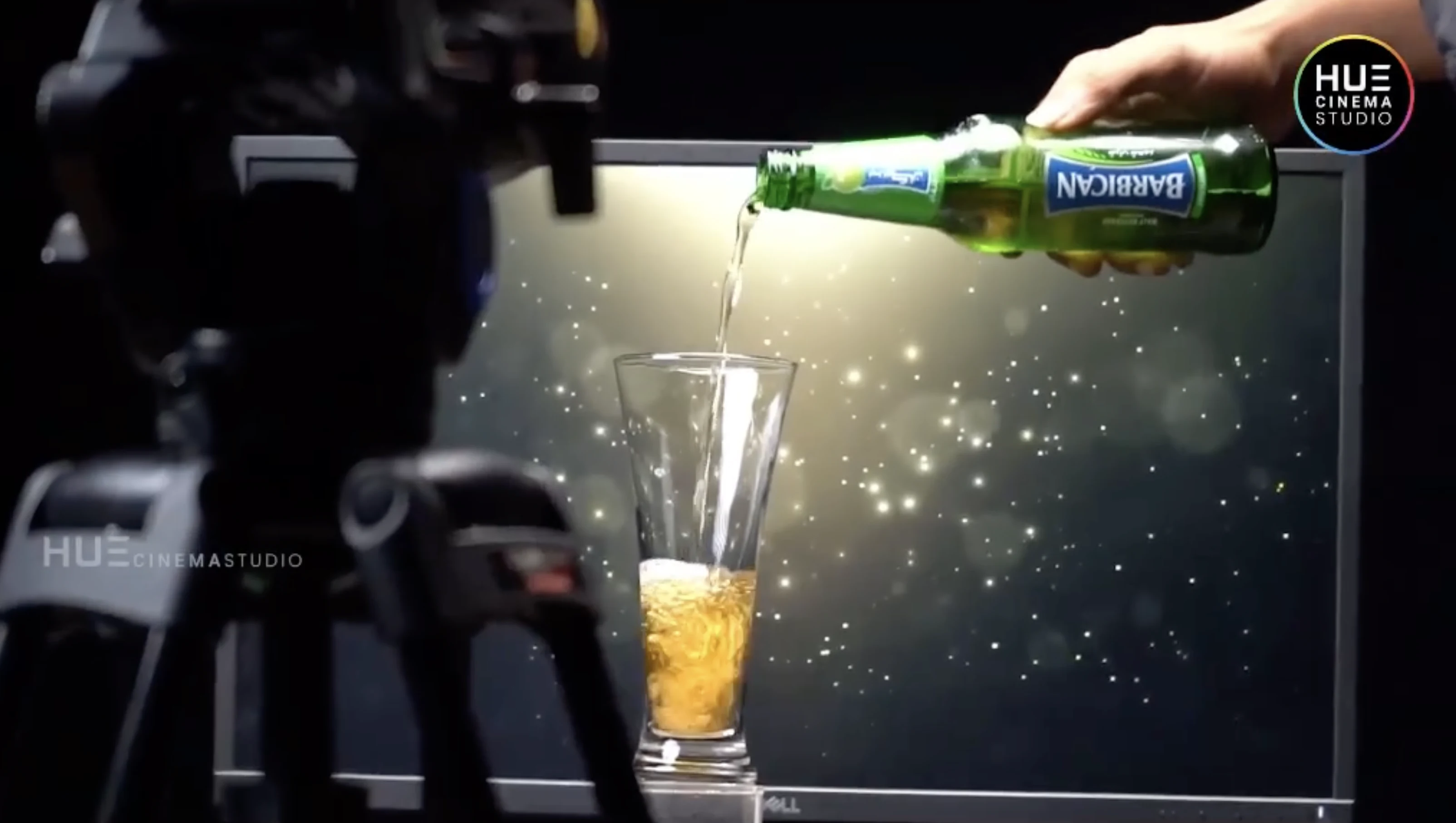 Director Haran Reddi's hand pouring Barbican apple-flavoured malt beverage into a glass beside a camera tripod, on the Alkor Cyber Space b-roll shoot, Hue Cinema Studio.